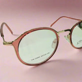 Round pinkish-red with a gold-tone Coonees Label Eyewear